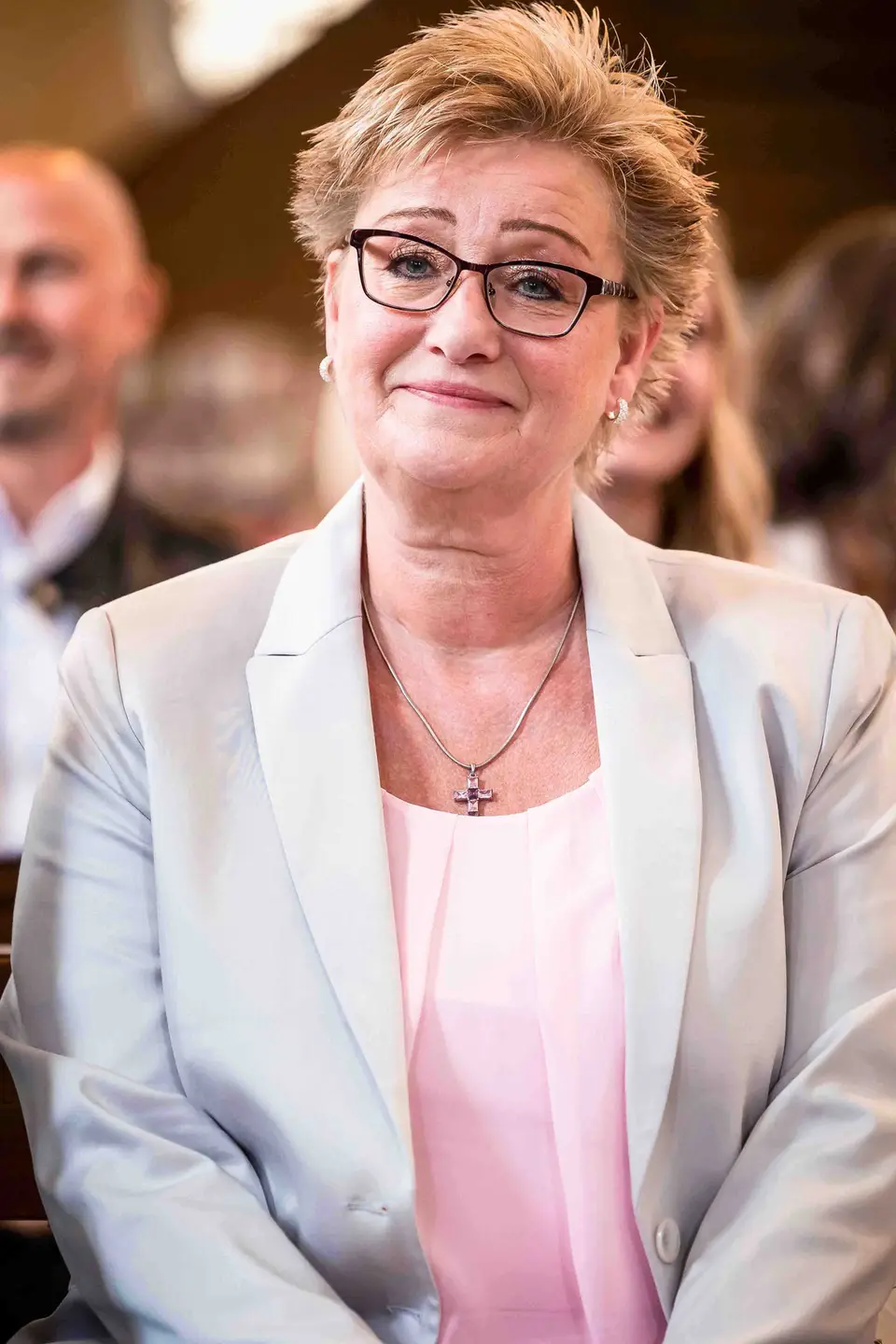 Gerührter Gast in heller Jacke lächelt in der Kirche
