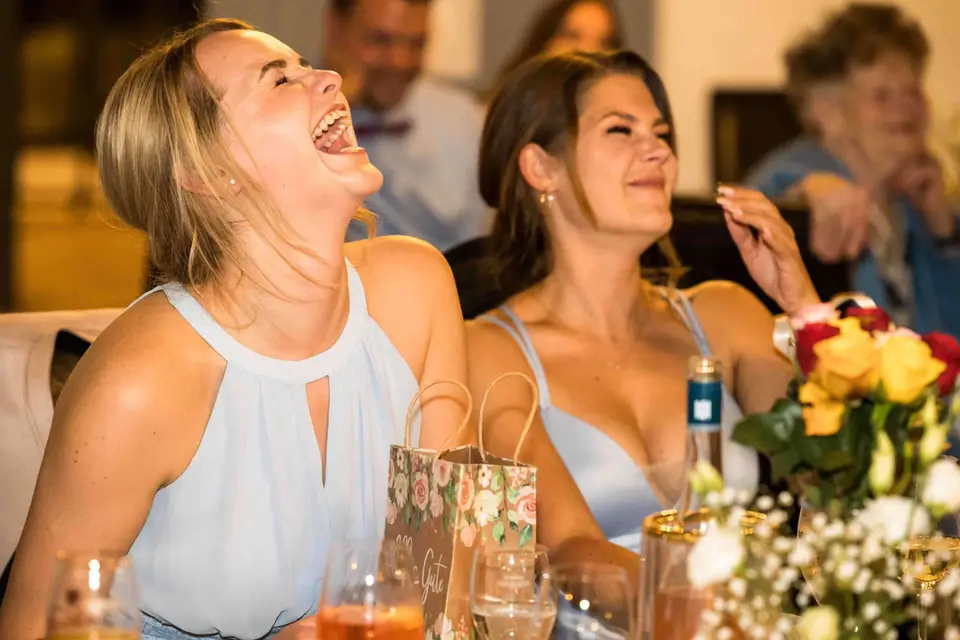 Zwei Gästinnen lachen herzhaft am festlich gedeckten Tisch