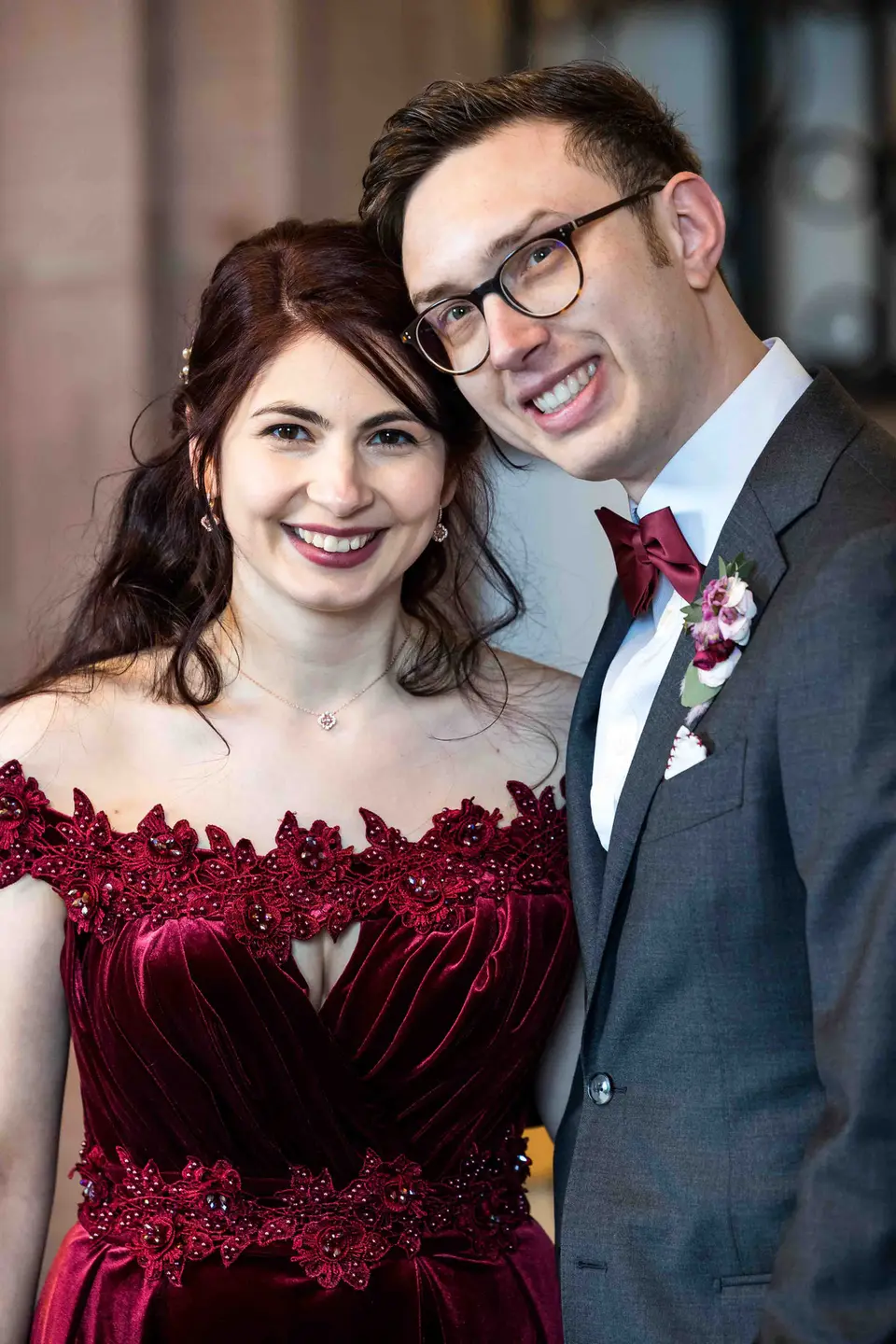 Brautpaar lacht Wange an Wange, Braut im roten Samtkleid