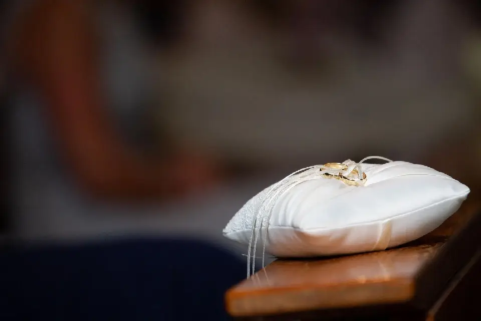 Eheringe auf einem weißen Ringkissen auf der Kirchenbank