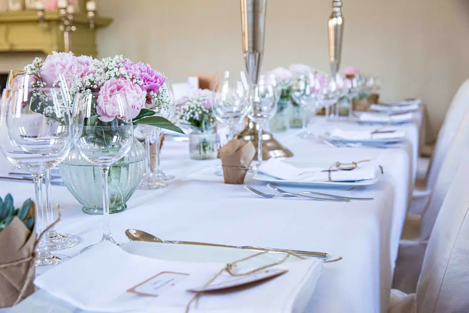 Festlich gedeckte Hochzeitstafel mit Gläsern und rosa Blumen