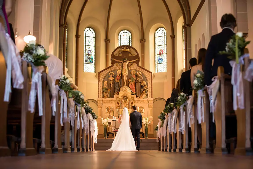 Blick durch den geschmückten Mittelgang zum Brautpaar vor dem Altar