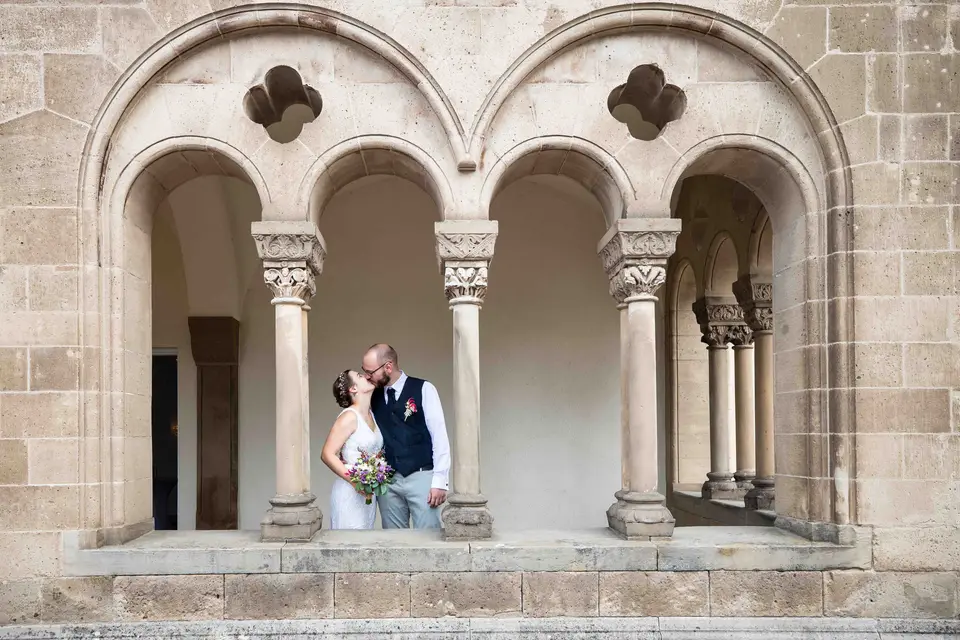 Brautpaar küsst sich unter romanischen Bögen am Schloss Bad Homburg