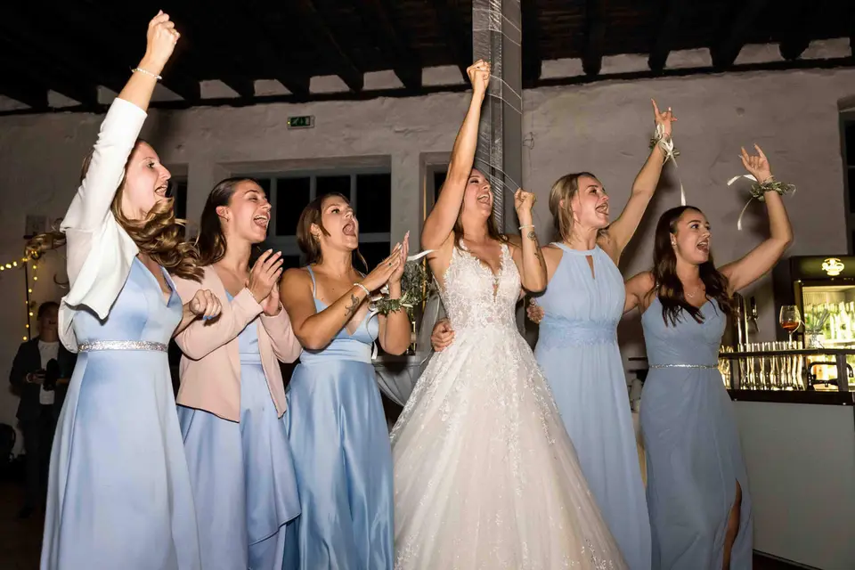 Braut und Brautjungfern feiern mit erhobenen Armen auf der Hochzeit