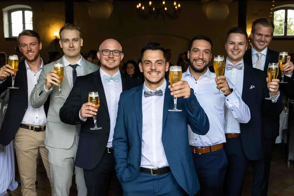 Männer in Anzügen stoßen gemeinsam mit Bier an