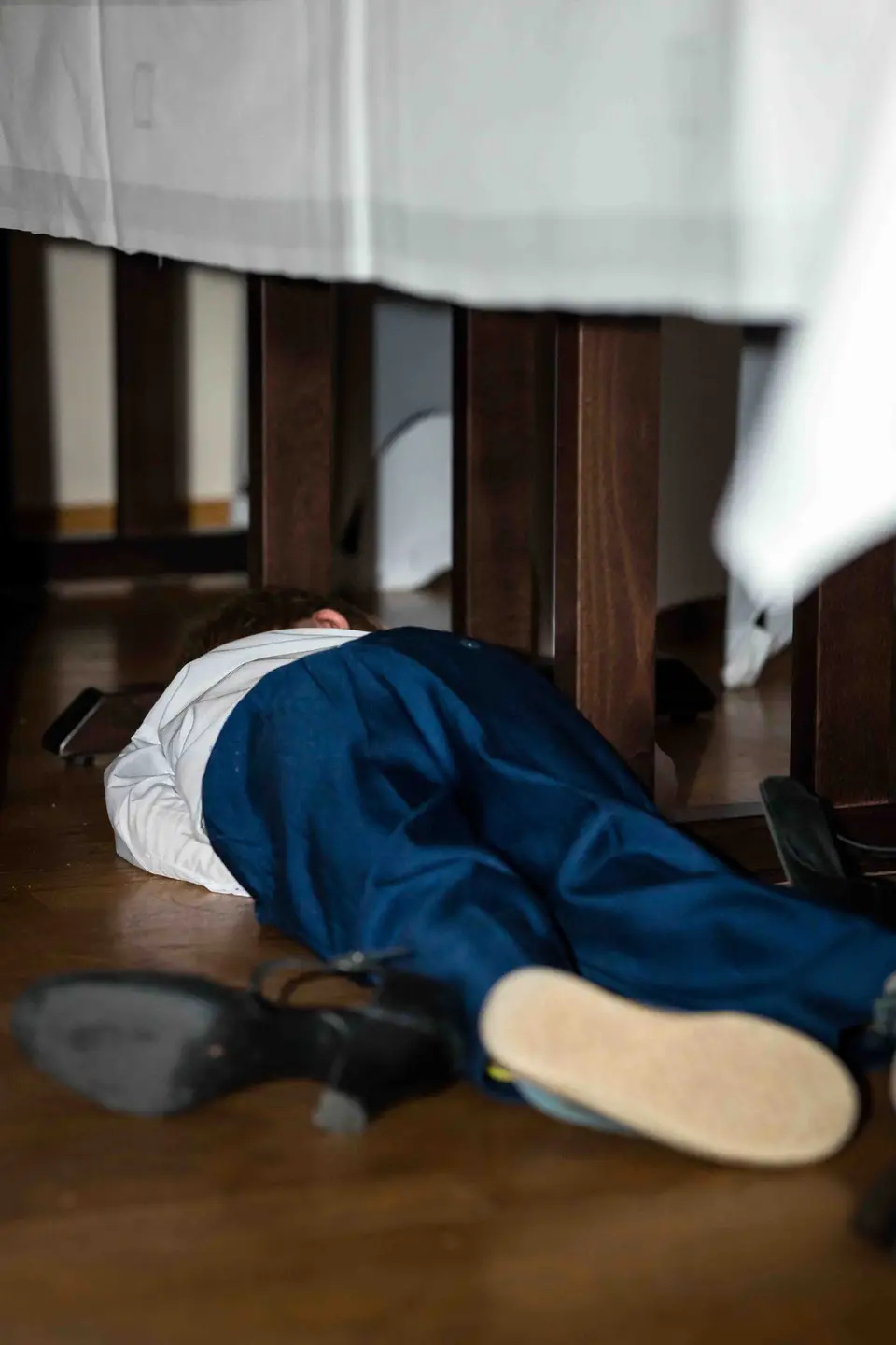 Bräutigam liegt zum Spaß unter einem Tisch auf dem Boden