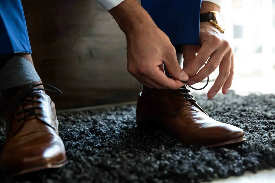 Bräutigam bindet seine braunen Schuhe zu