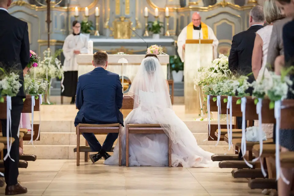 Brautpaar kniet vor dem Altar, der Pfarrer spricht den Segen