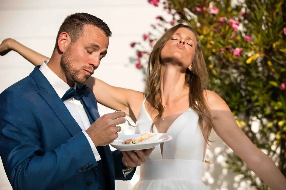 Brautpaar probiert die Hochzeitstorte, die Braut mit geschlossenen Augen