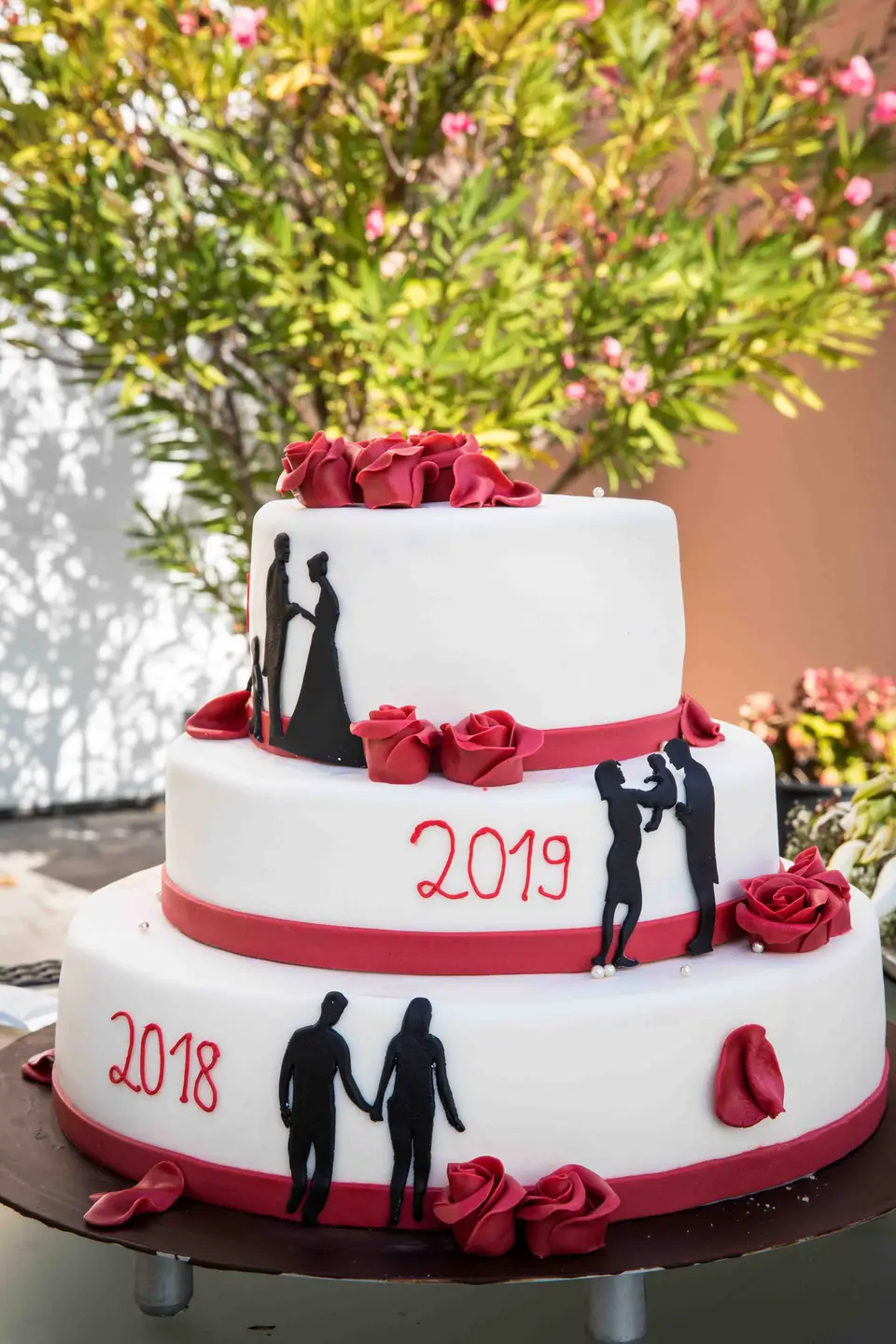 Dreistöckige Hochzeitstorte mit roten Rosen und Paar-Silhouetten