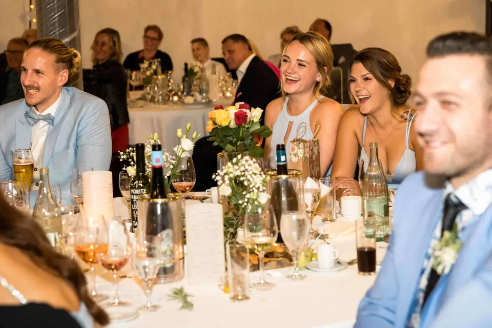 Gäste lachen fröhlich an der festlich gedeckten Tafel