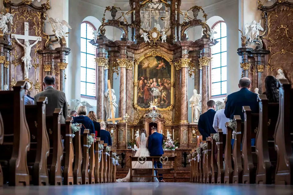 Kirchenbänke mit Gästen und prunkvoller Altarraum der Barockkirche