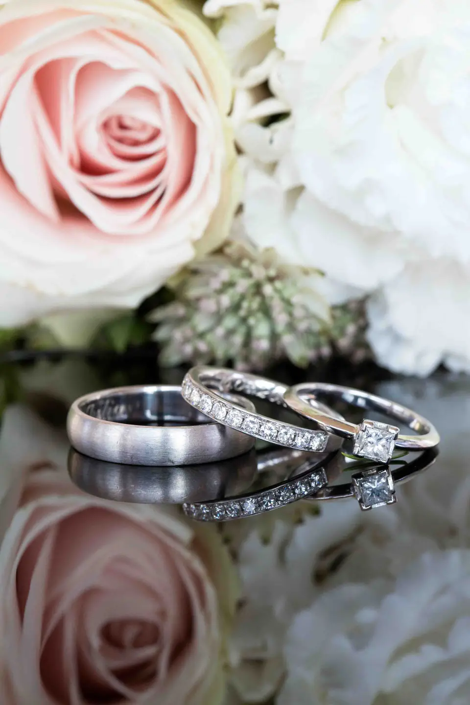 Drei Ringe auf einem Spiegel zwischen Rosen