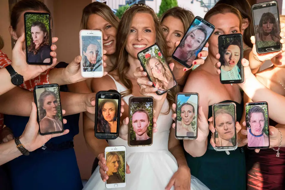 Braut und Freundinnen halten Handys mit Fotos ihrer Gesichter hoch