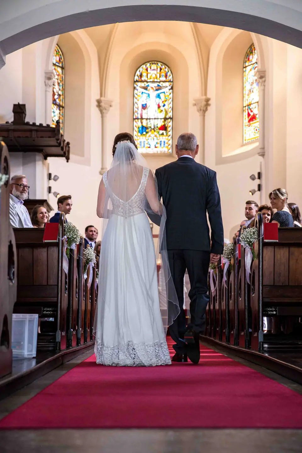 Braut geht mit ihrem Vater durch den Mittelgang zum Altar