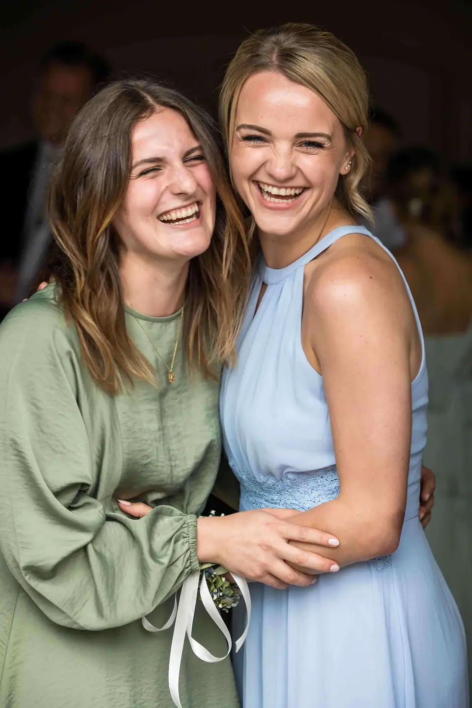 Zwei Freundinnen umarmen sich lachend auf der Hochzeit