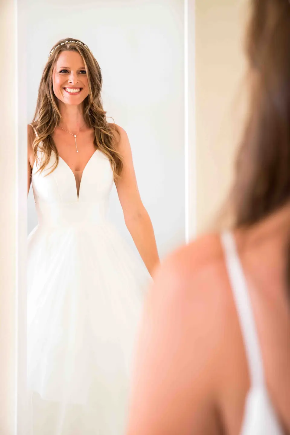 Braut zeigt sich lächelnd im fertigen Brautkleid