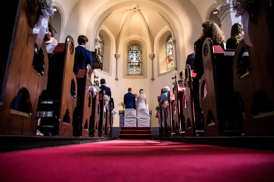 Blick über den roten Teppich im Mittelgang zum Brautpaar am Altar
