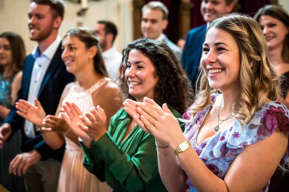 Lachende Gäste klatschen in den Kirchenbänken Beifall