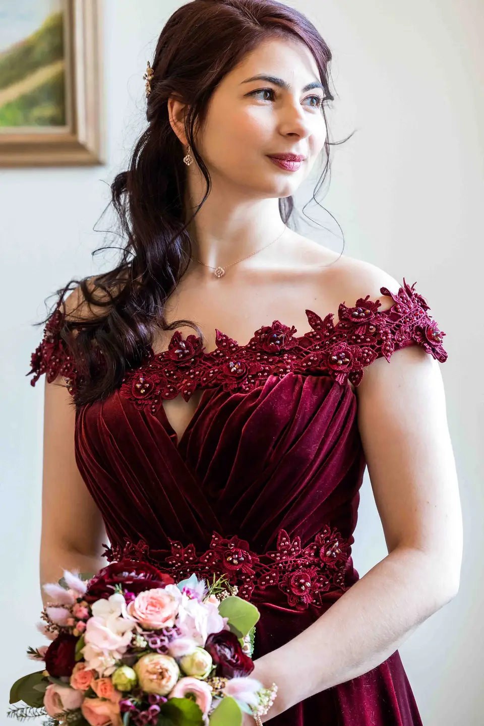Braut im dunkelroten schulterfreien Samtkleid mit Brautstrauß in der Hand