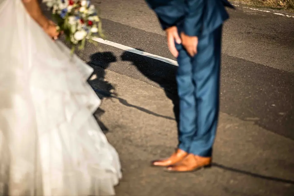 Brautkleid und Schuhe des Bräutigams mit Schatten auf dem Asphalt