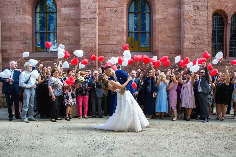 Gruppenbild vor der Kirche, Gäste lassen rote und weiße Herzballons steigen