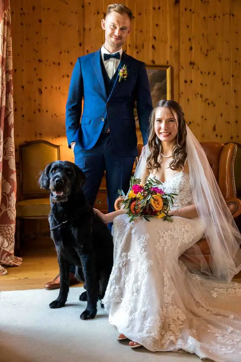 Brautpaar mit schwarzem Hund in einem holzgetäfelten Zimmer