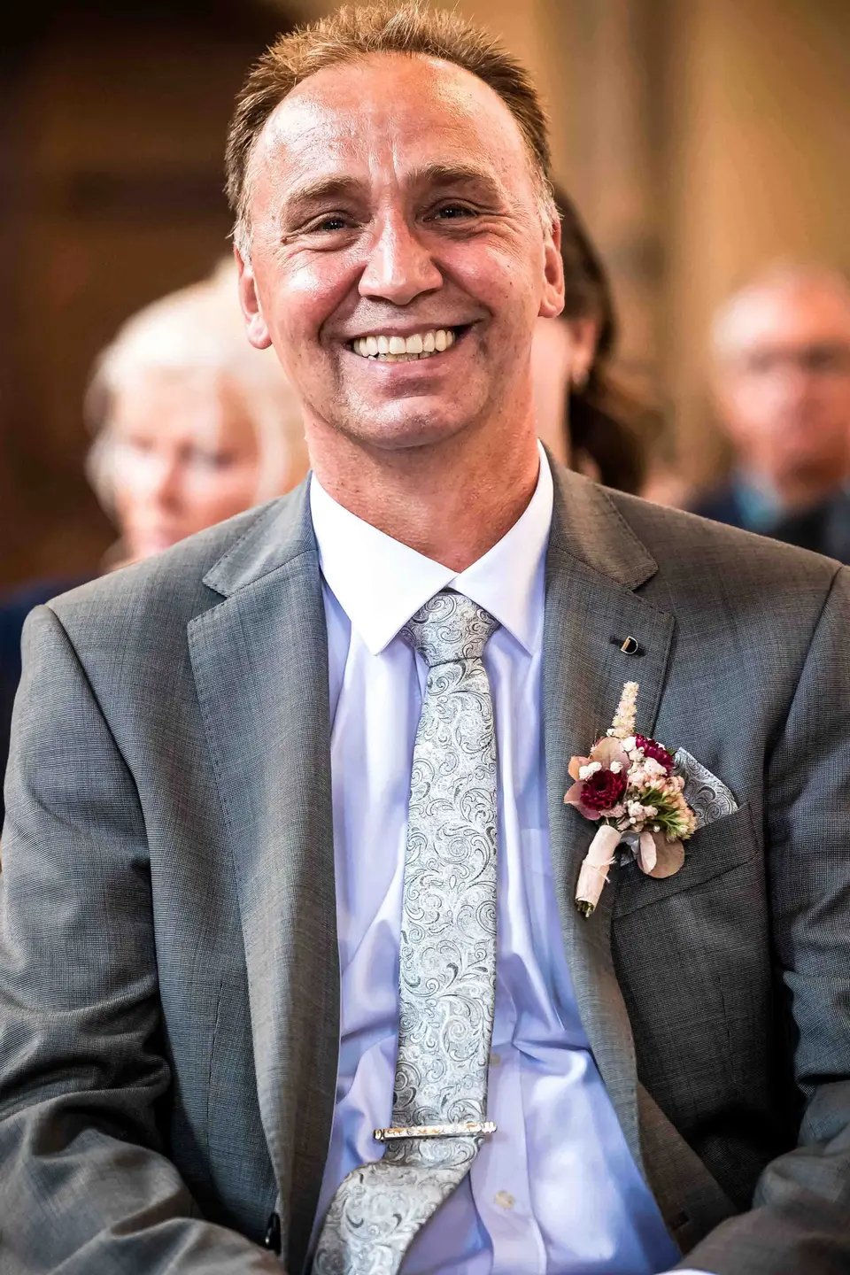 Lächelnder Vater der Braut mit Anstecker in der Kirchenbank