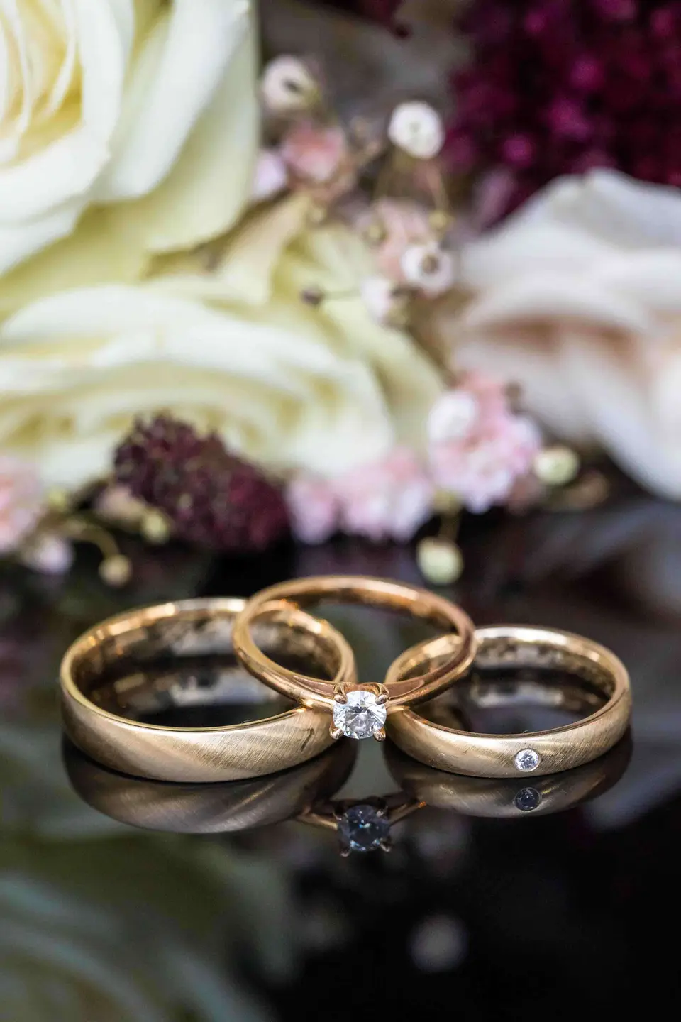 Eheringe und Verlobungsring als Detailaufnahme vor Blüten