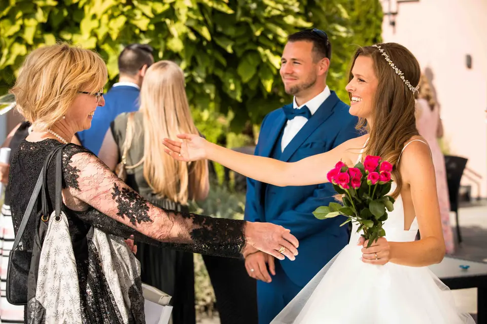 Gast gratuliert der Braut, die rote Rosen in der Hand hält