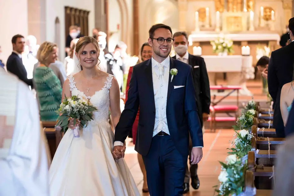 Das frisch verheiratete Brautpaar zieht lächelnd aus der Kirche aus