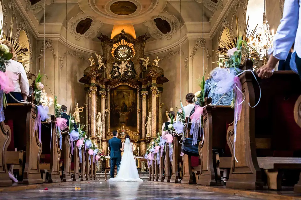 Blick durch die geschmückte Barockkirche auf das Brautpaar vor dem Altar